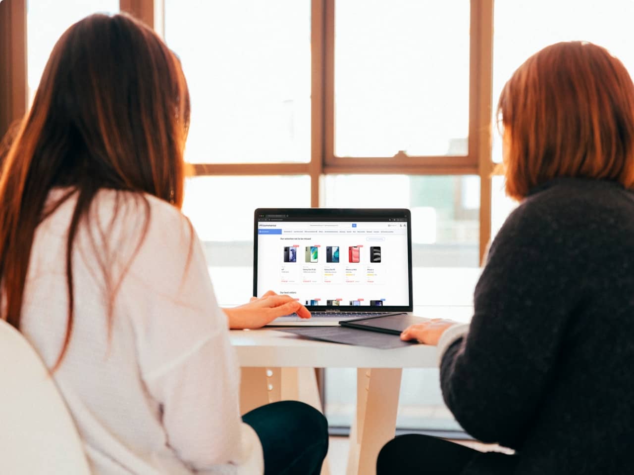 two women seen from behind, scrolling through a webshop